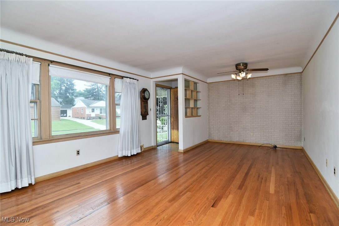 9421 David Road Cleveland, OH 44125 - Photo 7 of 36 Empty room with brick wall, light wood finished floors, and a ceiling fan