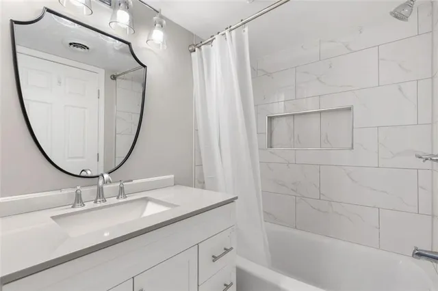 a bathroom with a granite countertop sink a mirror and a shower