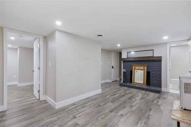 a view of an empty room with wooden floor and a fireplace