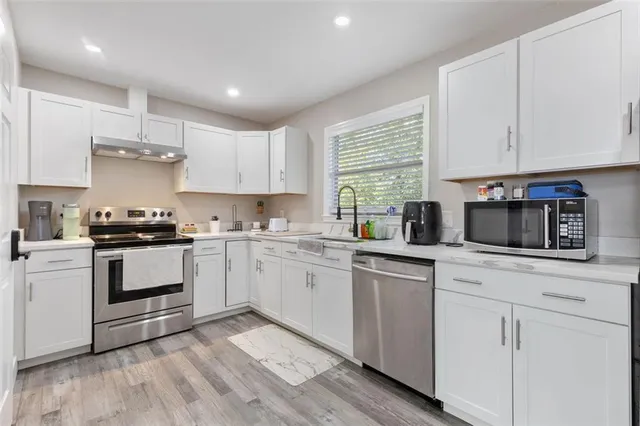 a kitchen with granite countertop white cabinets and white appliances