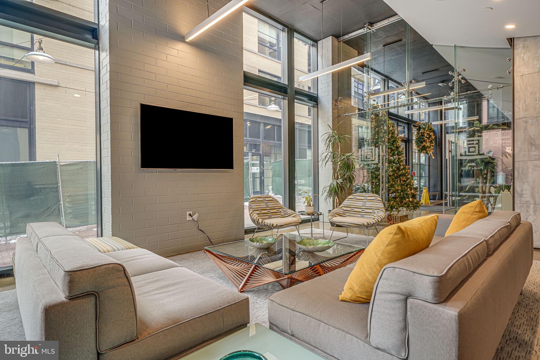 2125 14th Street Northwest, Unit 619 Washington, DC 20009 - Photo 9 of 22 a living room with furniture a flat screen tv and a floor to ceiling window