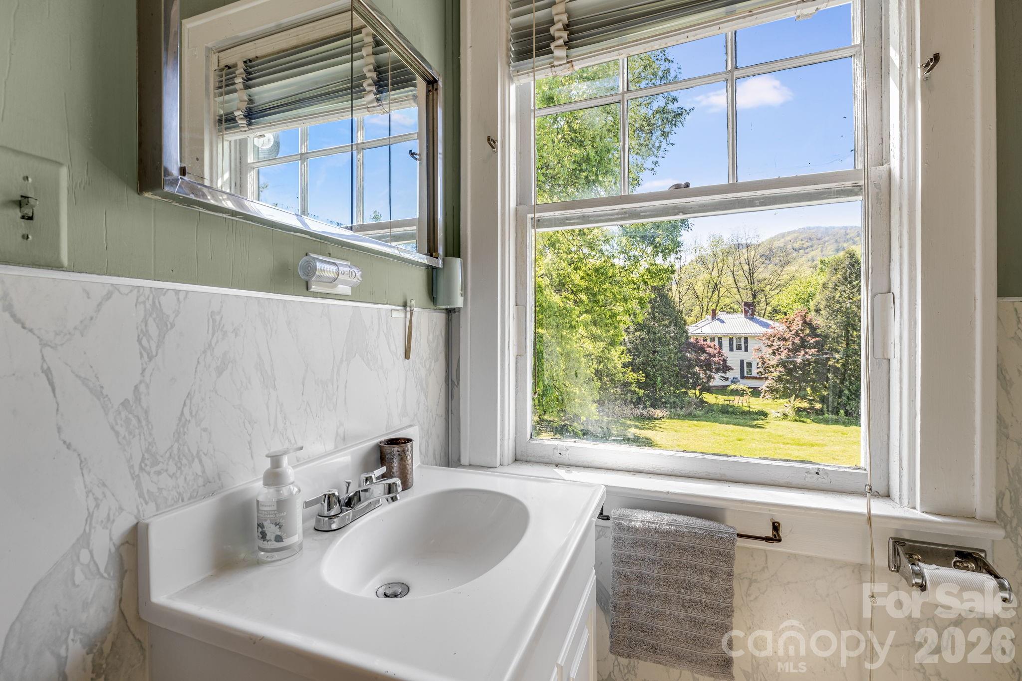 29 Walnut Street Hot Springs, NC 28743 - Photo 27 of 46 a bathroom with a granite countertop sink and a large mirror next to a window