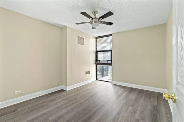an empty room with wooden floor and ceiling fan