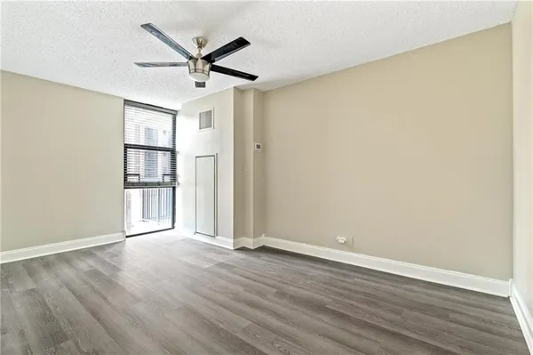 an empty room with wooden floor and ceiling fan
