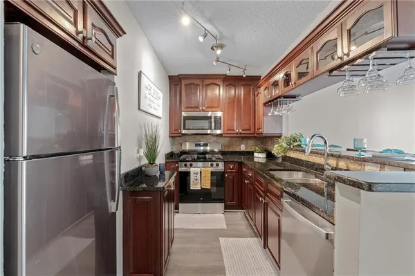 a kitchen with stainless steel appliances granite countertop a refrigerator a stove and a sink