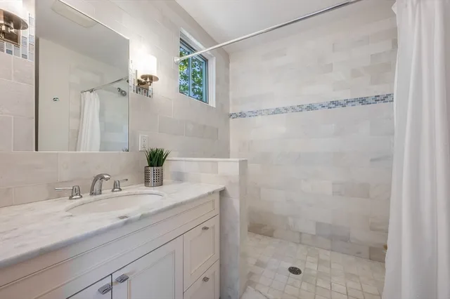 a bathroom with a granite countertop shower sink and mirror