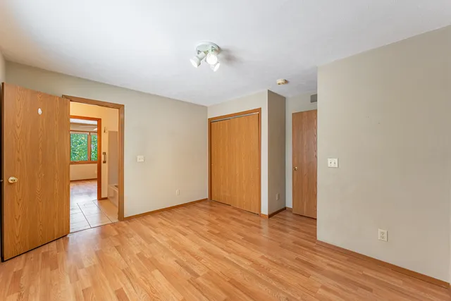 a view of an empty room with wooden floor and closet