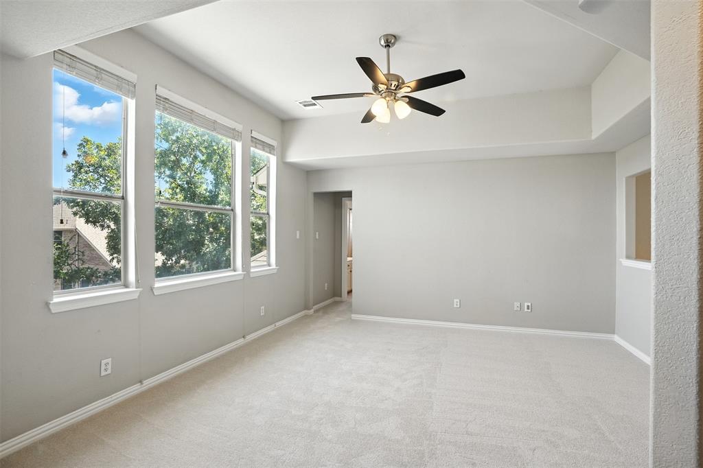 8220 Holliday Road Lantana, TX 76226 - Photo 29 of 40 Spacious room featuring three large windows, light gray walls, plush carpet, and a ceiling fan