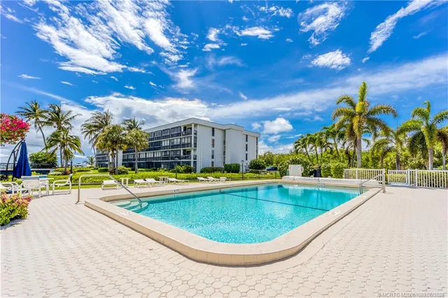 a view of a swimming pool with a lawn chairs under an umbrella