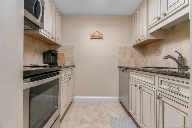 a kitchen with granite countertop a sink stove and cabinets