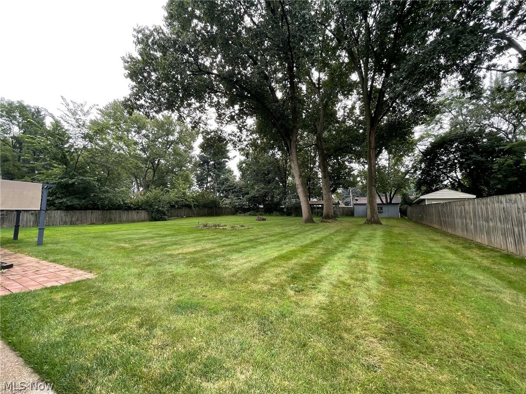 686 Shook Road Akron, OH 44319 - Photo 7 of 22 Expansive green lawn with mature trees, a privacy fence, and a paver patio