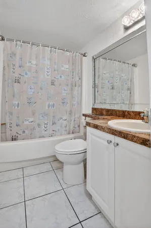 a bathroom with a granite countertop bathtub sink vanity mirror and toilet