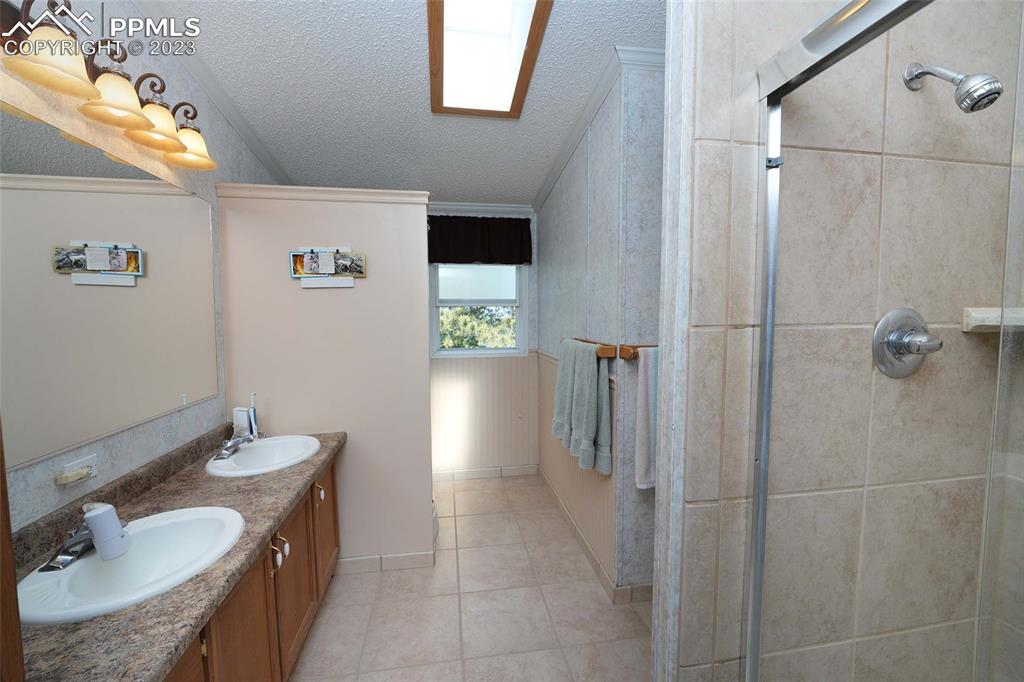 187 Blue Spruce Road Divide, CO 80814 - Photo 10 of 31 a bathroom with a granite countertop sink a mirror and shower