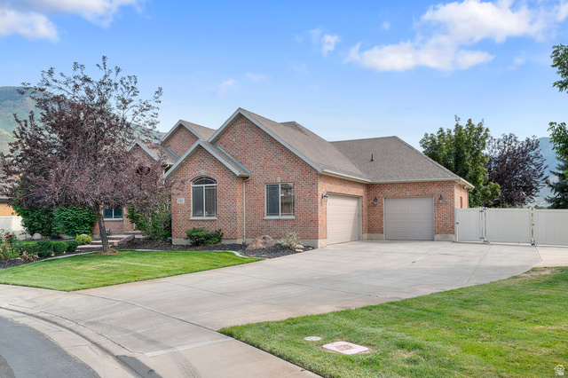 1501 West Elk Circle Mapleton, UT 84664 - Photo 3 of 39 Brick exterior with multiple gables, arched window, attached two-car garage, expansive concrete driveway, and white privacy fence