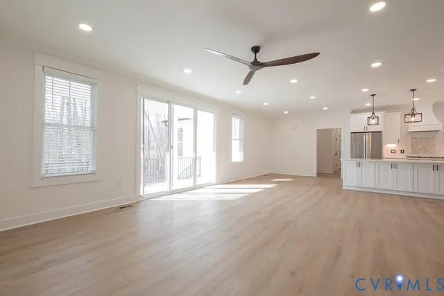 a view of an empty room with a window and wooden floor