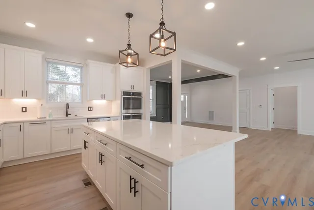 a large kitchen with stainless steel appliances a large counter top a sink a refrigerator and a window