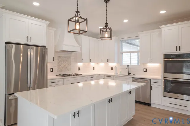 a kitchen with stainless steel appliances a sink a stove a refrigerator cabinets and wooden floor