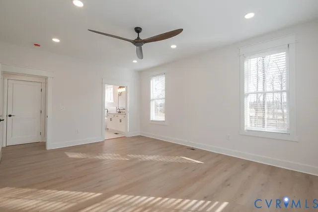 a view of an empty room with a window and wooden floor