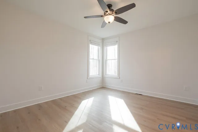 an empty room with a window and a fan
