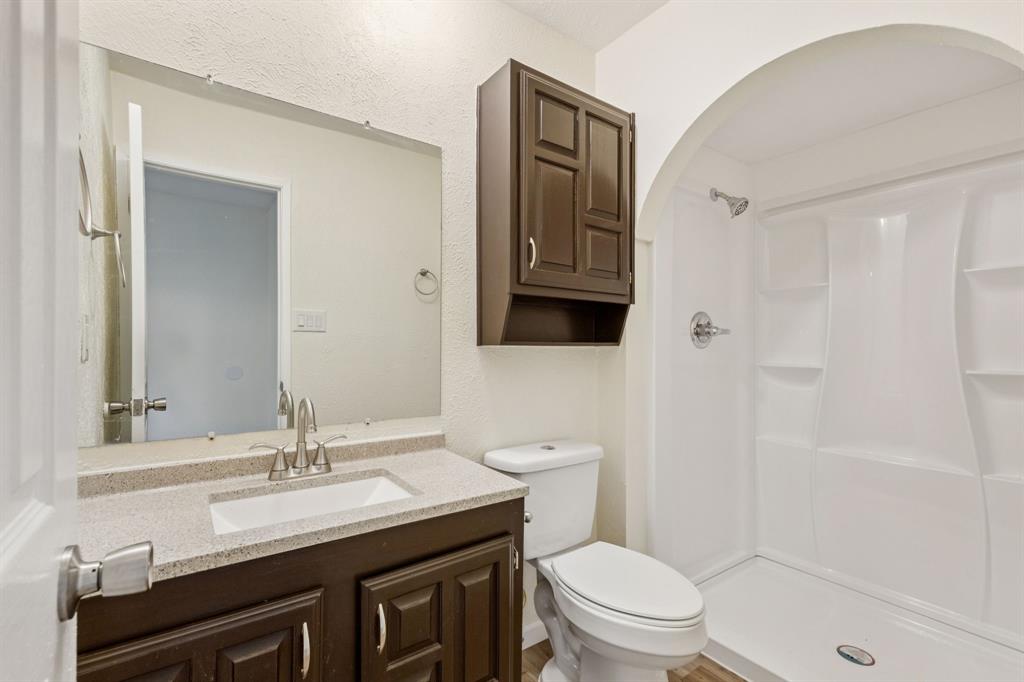 9305 Pollard Street Rowlett, TX 75088 - Photo 22 of 30 a bathroom with a sink a toilet a mirror and shower
