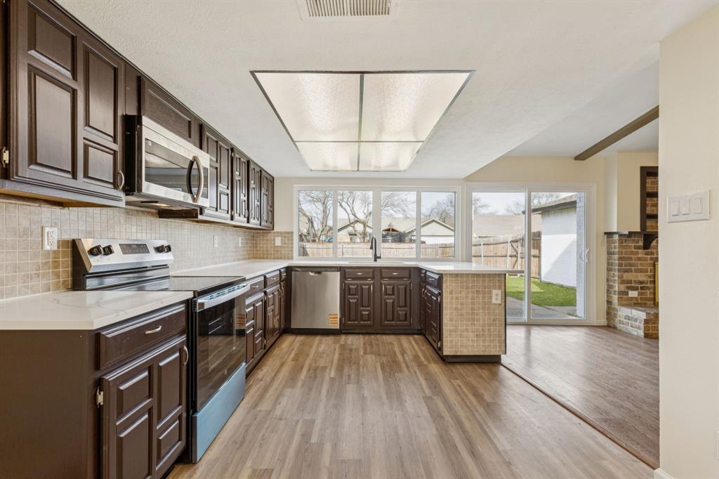 9305 Pollard Street Rowlett, TX 75088 - Photo 7 of 30 a large kitchen with stainless steel appliances granite countertop a lot of counter space and wooden floors