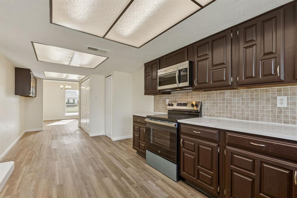 9305 Pollard Street Rowlett, TX 75088 - Photo 8 of 30 a kitchen with stainless steel appliances granite countertop wooden cabinets a stove top oven a sink and dishwasher