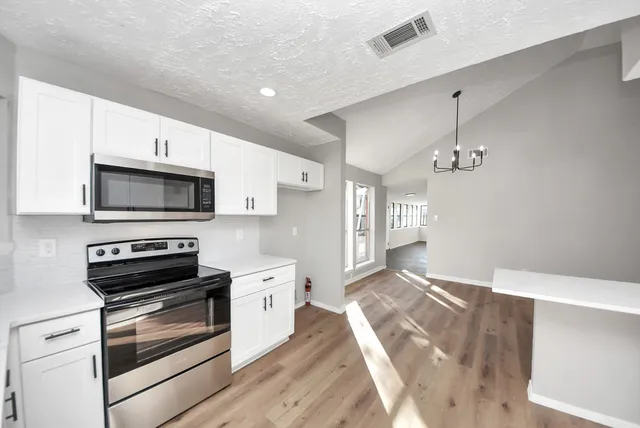 a kitchen with stainless steel appliances granite countertop a stove a sink and white cabinets