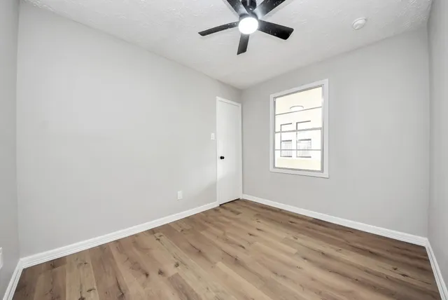 a view of empty room with wooden floor and fan