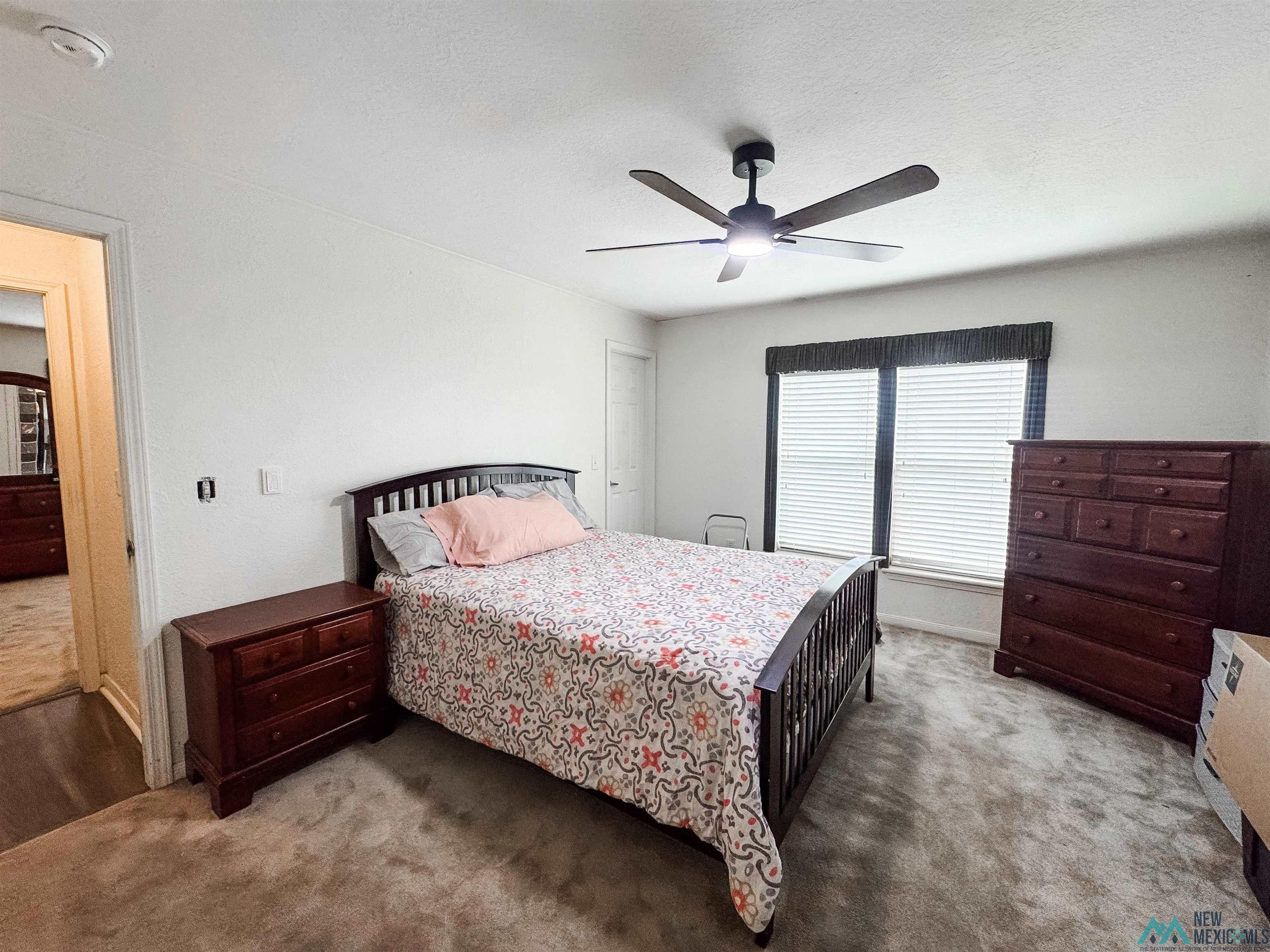 309 Crossbow Road Artesia, NM 88210 - Photo 26 of 31 Neutral paint palette with ceiling fan, two large windows with blinds, and carpeted flooring