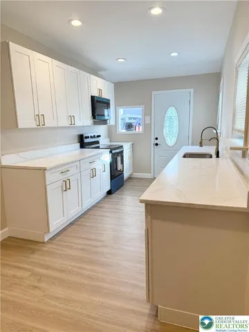 a kitchen with granite countertop a sink cabinets and wooden floor