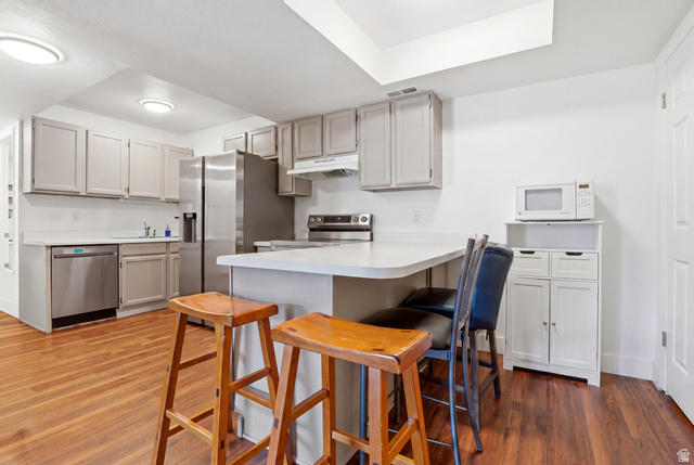 88 West 50 South, Unit P10 Centerville, UT 84014 - Photo 7 of 20 Kitchen with a breakfast bar area, light countertops, stainless steel appliances, a peninsula, and dark wood-style floors