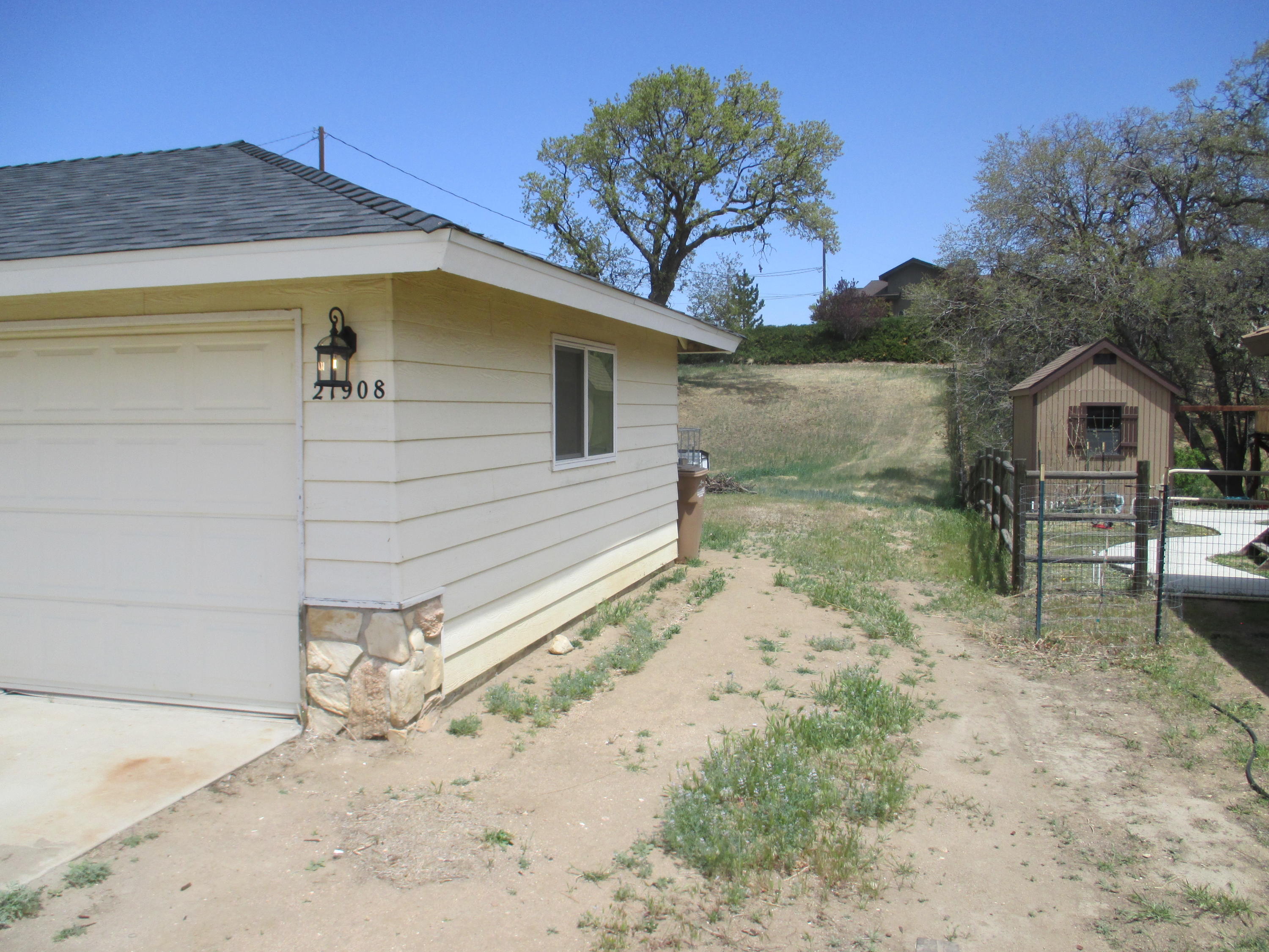 21908 Mariposa Road Tehachapi, CA 93561 - Photo 18 of 23 a view of a small yard in front of a house with a large tree