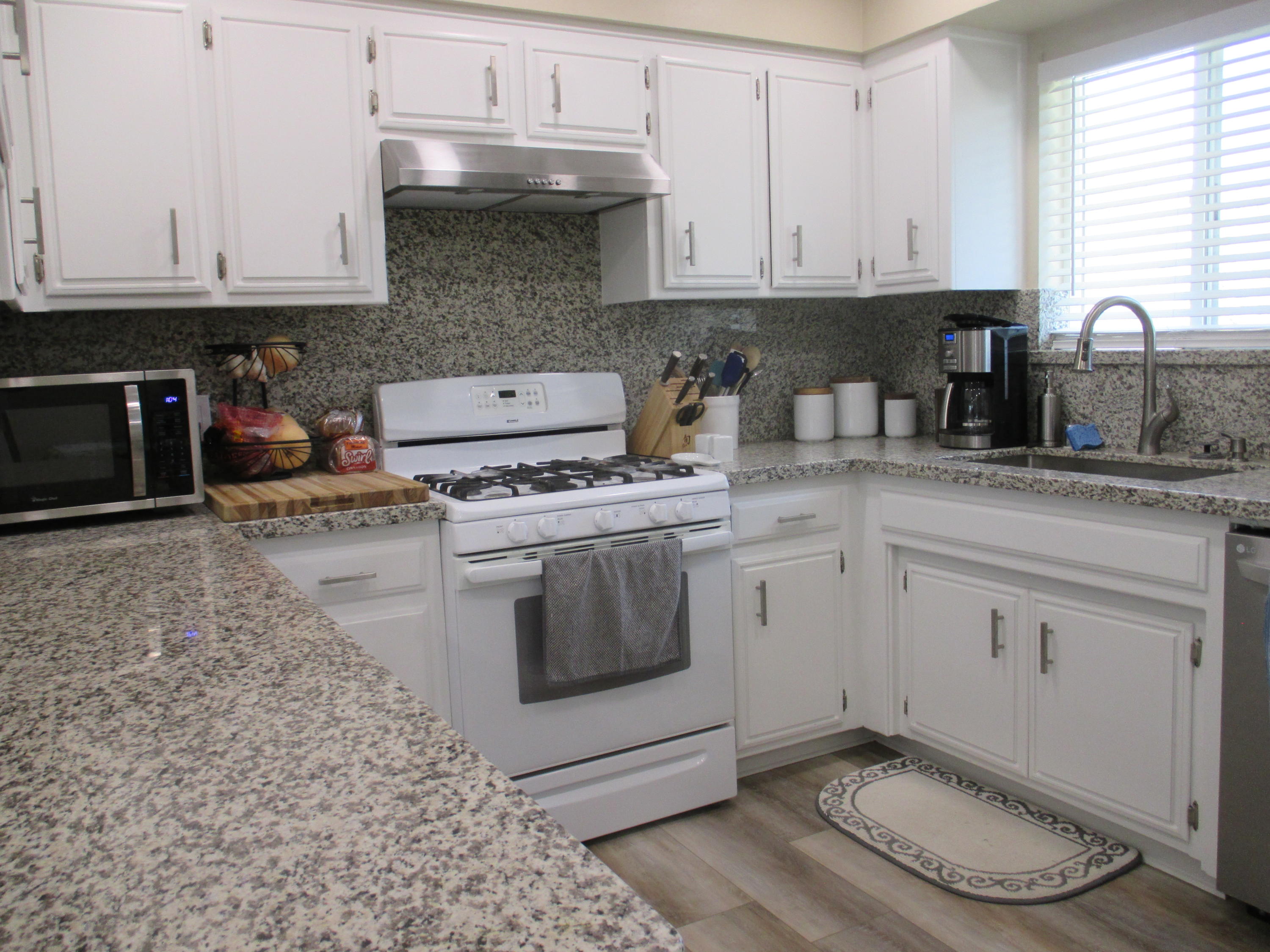 21908 Mariposa Road Tehachapi, CA 93561 - Photo 4 of 23 a kitchen with granite countertop white cabinets and white appliances