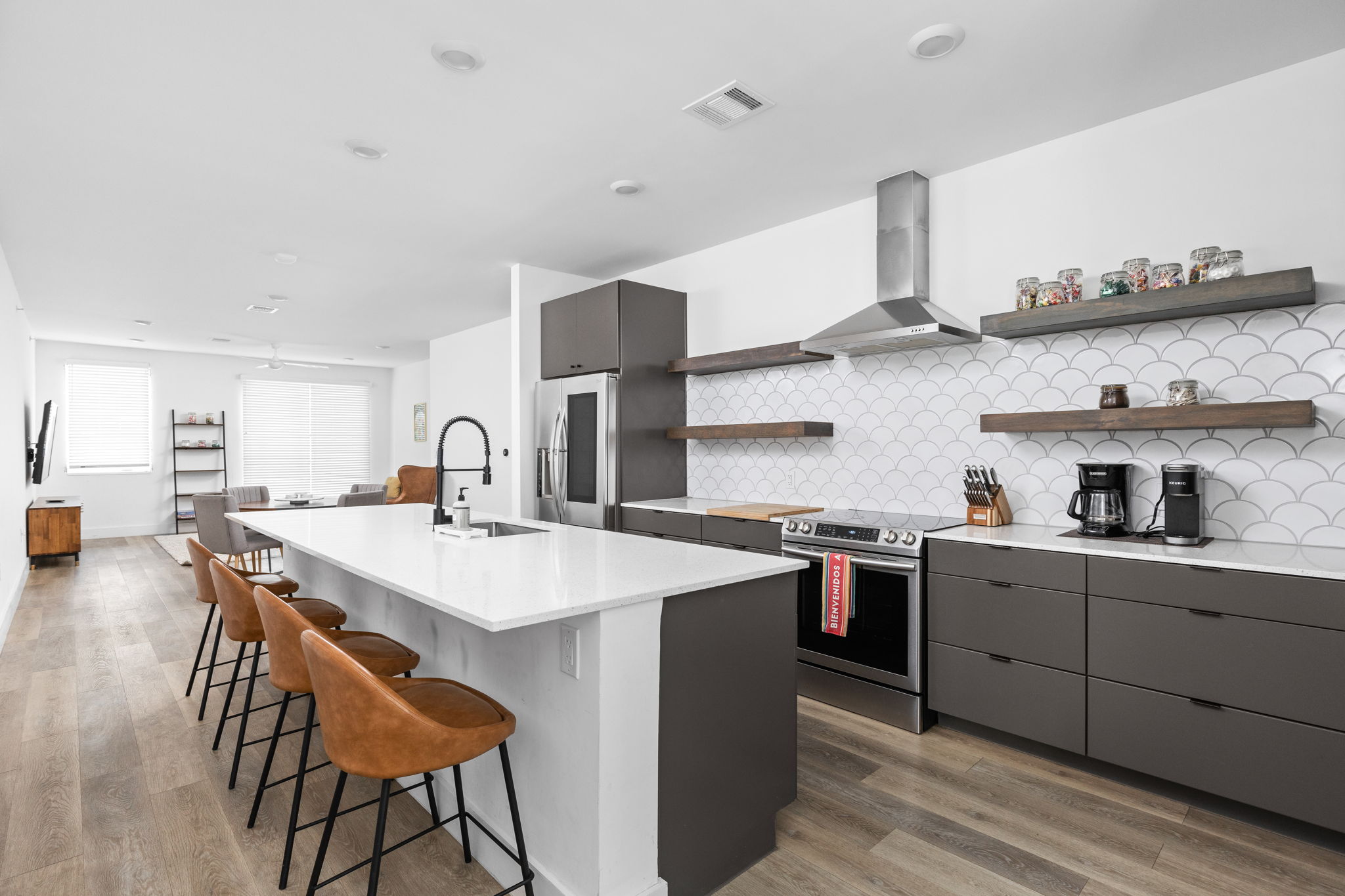 a kitchen with stainless steel appliances a sink a stove a refrigerator dining table and chairs