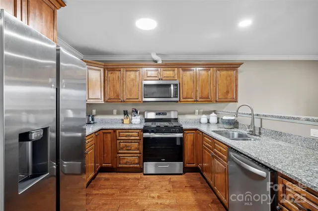 a kitchen with granite countertop a sink a stove and cabinets