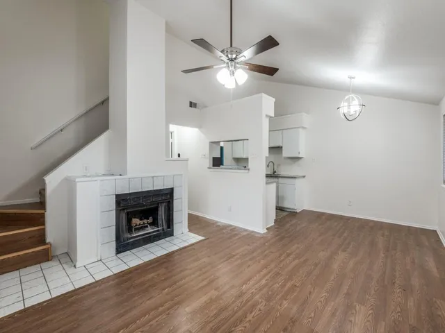 a view of a livingroom with a fireplace a ceiling fan and wooden floor