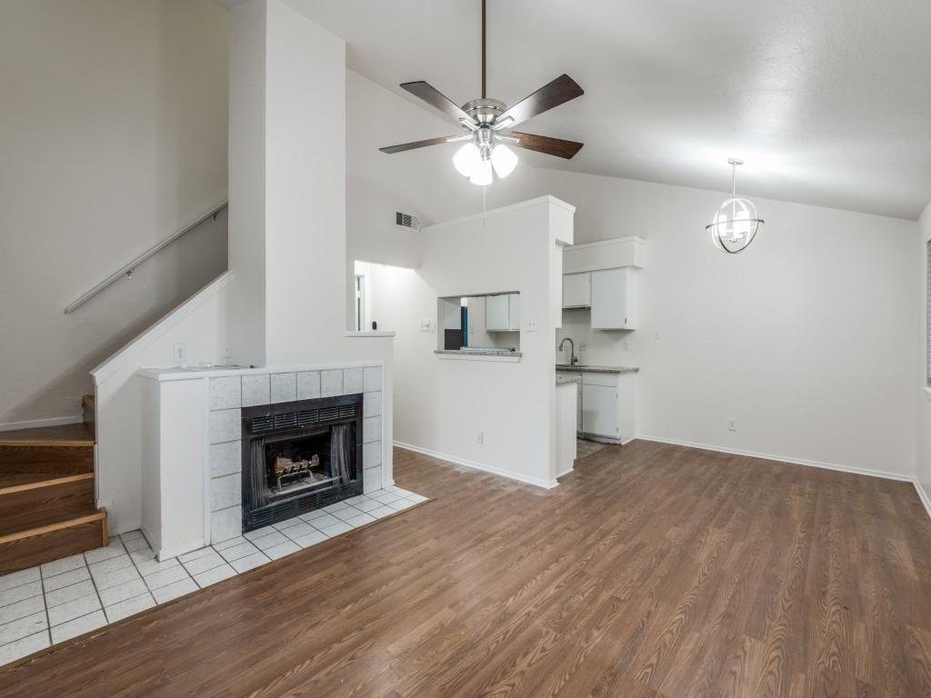 a view of a livingroom with a fireplace a ceiling fan and wooden floor