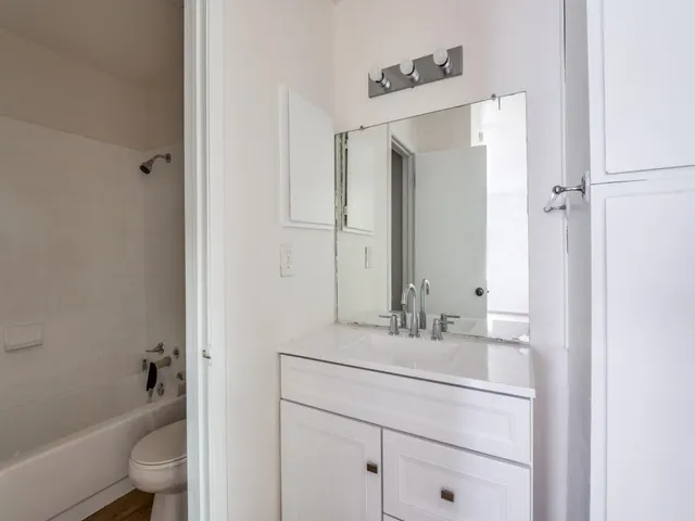 a bathroom with a bathtub shower sink vanity mirror and toilet