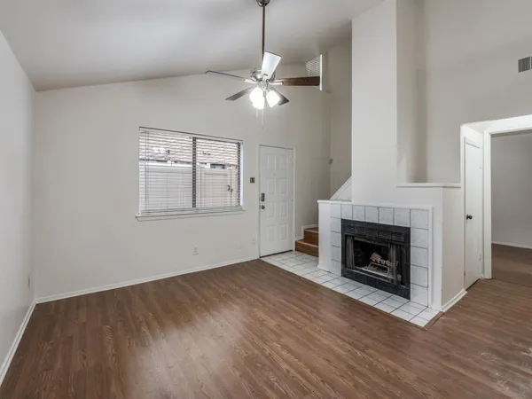 a view of empty room with wooden floor fireplace and fan