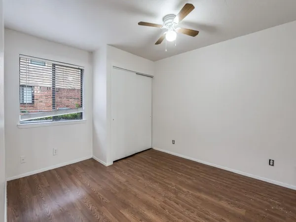 an empty room with wooden floor fan and windows