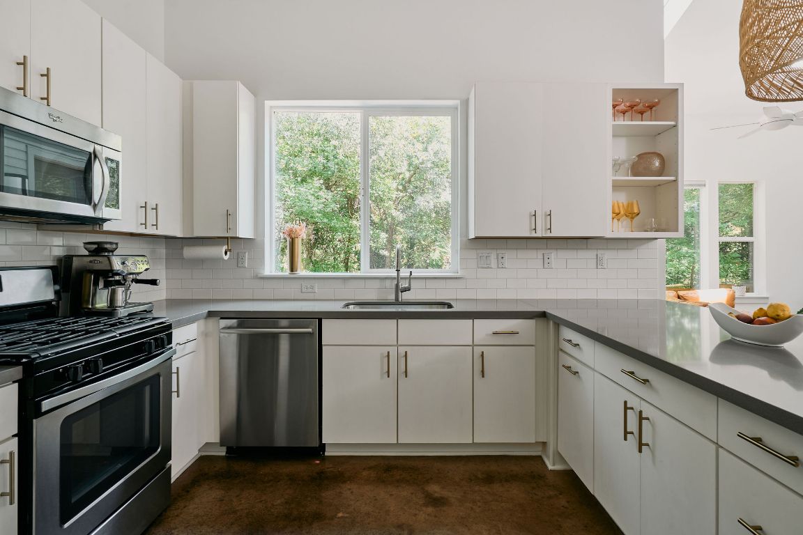 3001 Del Curto Road, Unit 14 Austin, TX 78704 - Photo 6 of 18 a kitchen with stainless steel appliances granite countertop white cabinets a sink a stove a microwave and wooden cabinets