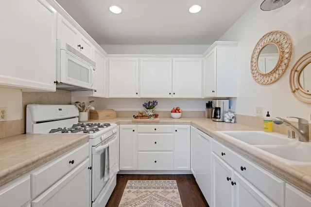 a kitchen with granite countertop white cabinets white stainless steel appliances and a sink