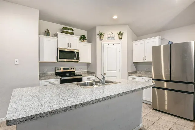 a kitchen with granite countertop a refrigerator and a sink