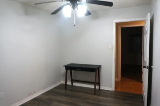 an empty room with wooden floor closet fan and windows