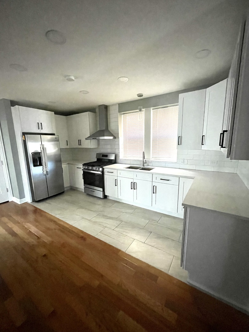 4969 North Kilpatrick Avenue, Unit 1 Chicago, IL 60630 - Photo 2 of 6 a large kitchen with cabinets wooden floor and stainless steel appliances