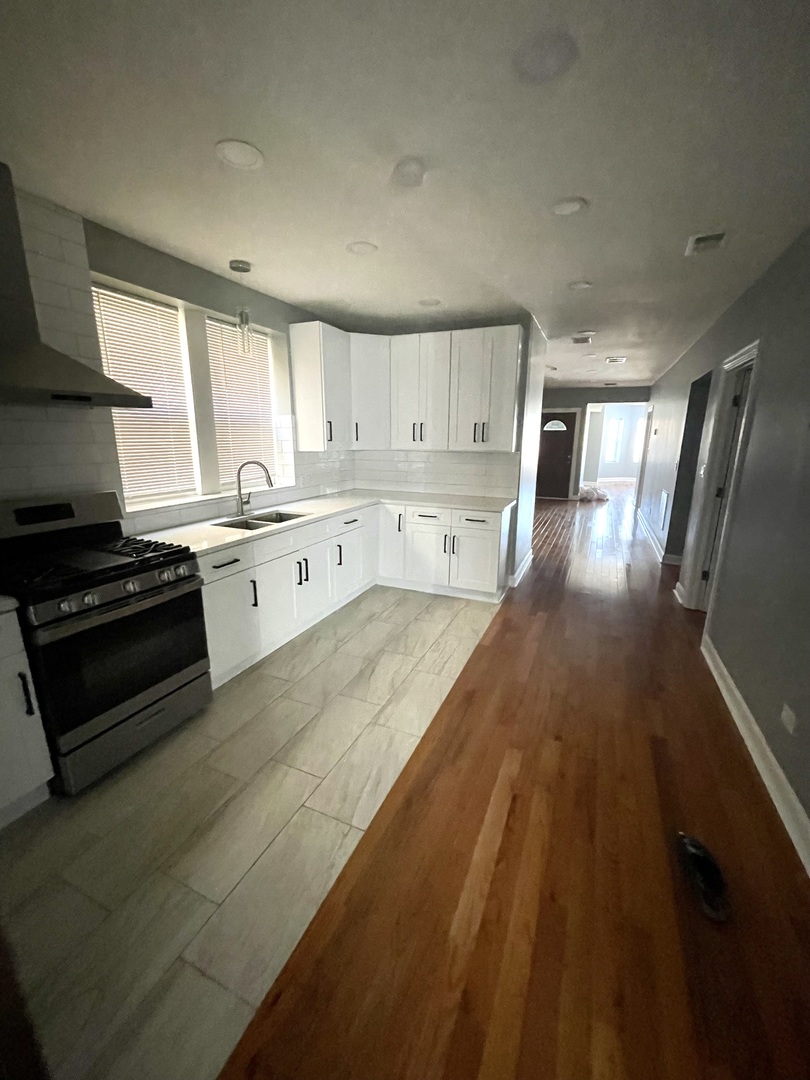 4969 North Kilpatrick Avenue, Unit 1 Chicago, IL 60630 - Photo 3 of 6 a large kitchen with stainless steel appliances granite countertop a stove a sink dishwasher and a refrigerator