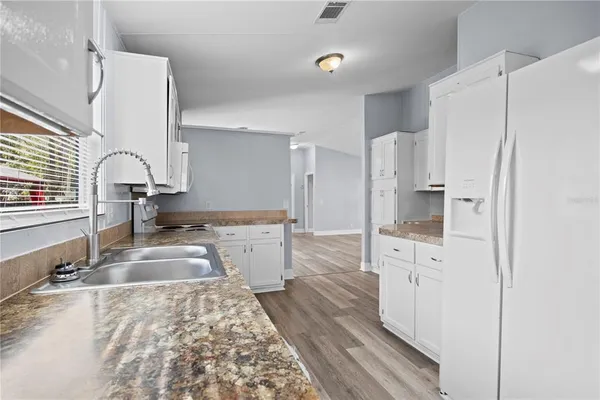 a large kitchen with a refrigerator a sink and white cabinets