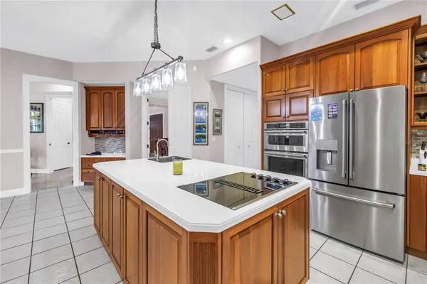 a kitchen that has a kitchen island wooden cabinets a refrigerator and a sink