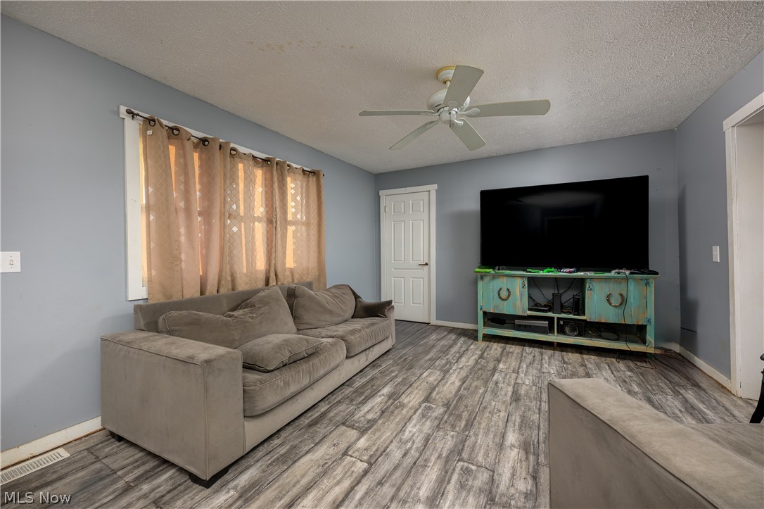 8200 Cutler Road Southwest Sherrodsville, OH 44675 - Photo 12 of 26 Living area with a textured ceiling, a ceiling fan, and wood finished floors
