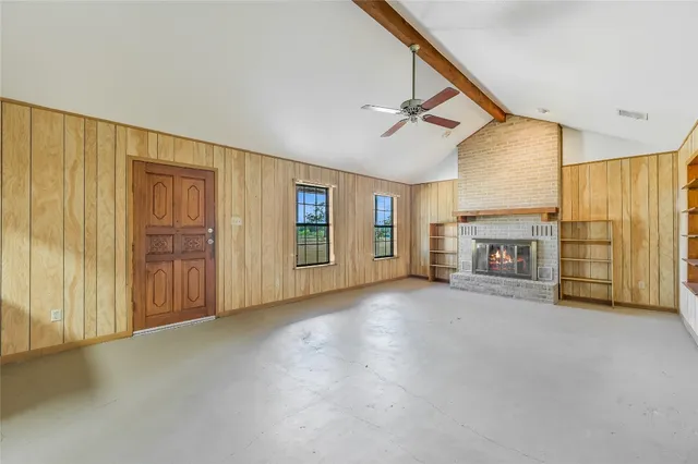 a view of an empty room with a window and a kitchen